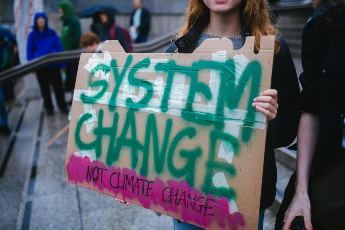 Environmental activists with a sign that says "System change, not climate change".